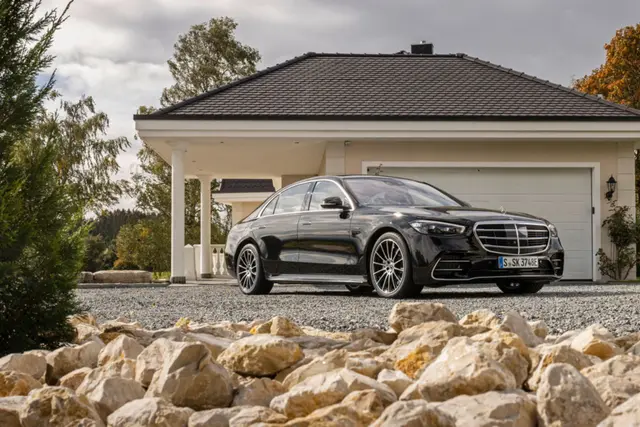 Une Mercedes Classe S limousine stationnée devant une maison