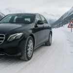 Mercedes Classe E circulant sur une route de montagne enneigée, illustrant les conditions hivernales visées par la loi Montagne.