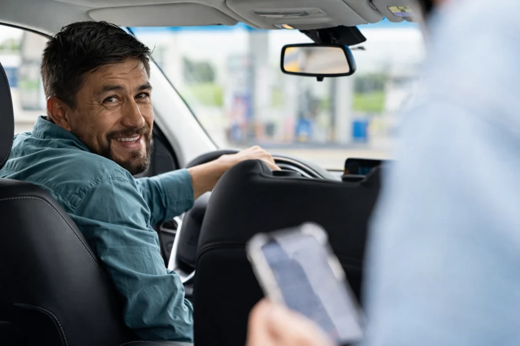 Chauffeur VTC souriant au volant avec un passager à l’arrière